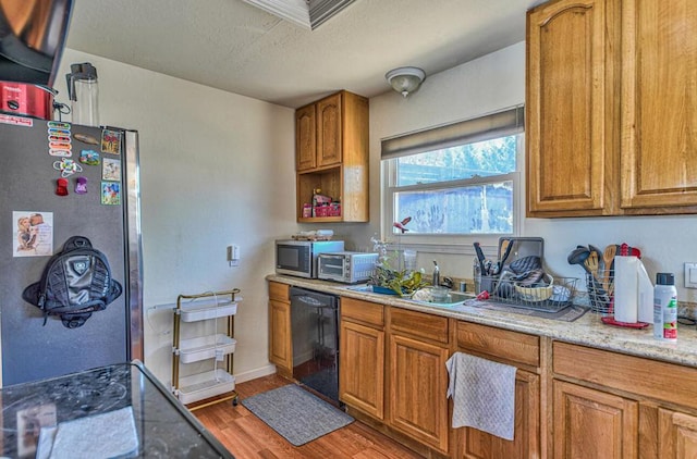 kitchen featuring hardwood / wood-style flooring, stainless steel appliances, sink, and light stone counters