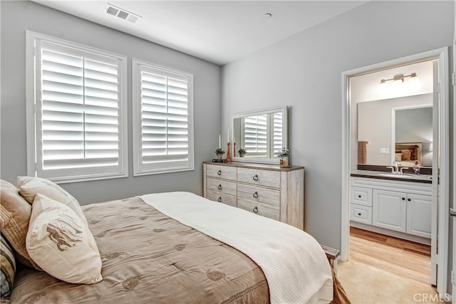 bedroom featuring sink, connected bathroom, and light hardwood / wood-style floors