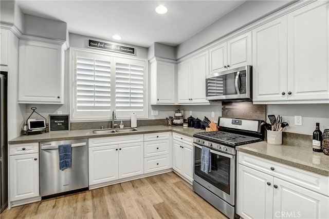 kitchen with stainless steel appliances, light hardwood / wood-style flooring, white cabinets, and sink