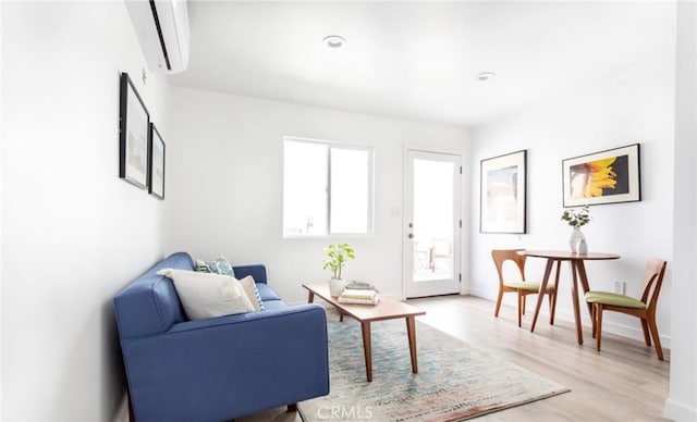 living area featuring a wall unit AC and light hardwood / wood-style flooring