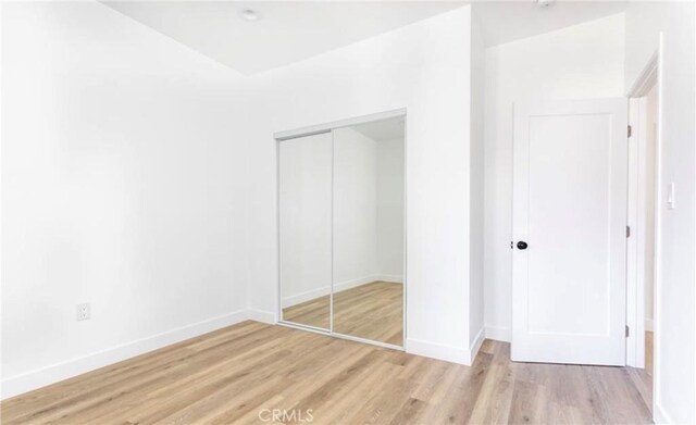 unfurnished bedroom with a closet and light hardwood / wood-style floors