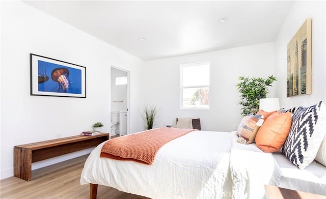 bedroom with ensuite bathroom and light wood-type flooring