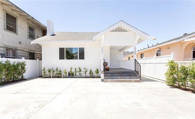 view of front facade featuring a patio area, fence, a chimney, and stucco siding