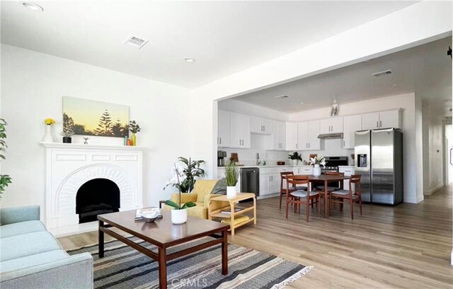 living room featuring sink, light hardwood / wood-style flooring, and a fireplace