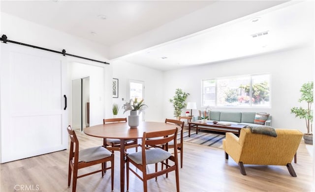 dining room with light hardwood / wood-style flooring and a barn door