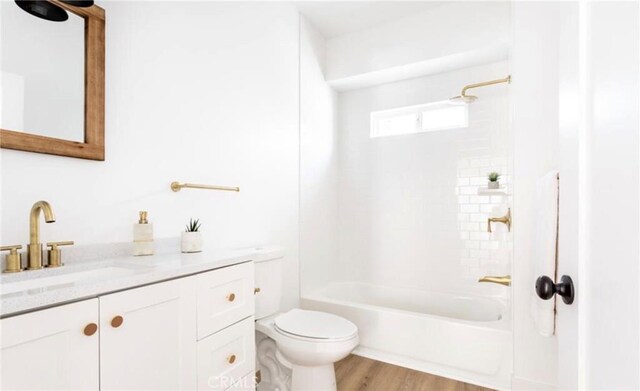 full bathroom with vanity, tiled shower / bath, hardwood / wood-style floors, and toilet