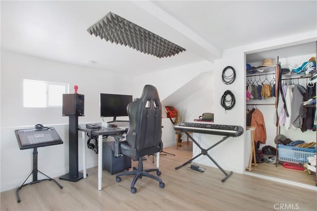 home office featuring beamed ceiling, light wood-type flooring, and baseboards