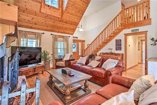 living room with high vaulted ceiling, a skylight, wood ceiling, and light hardwood / wood-style flooring