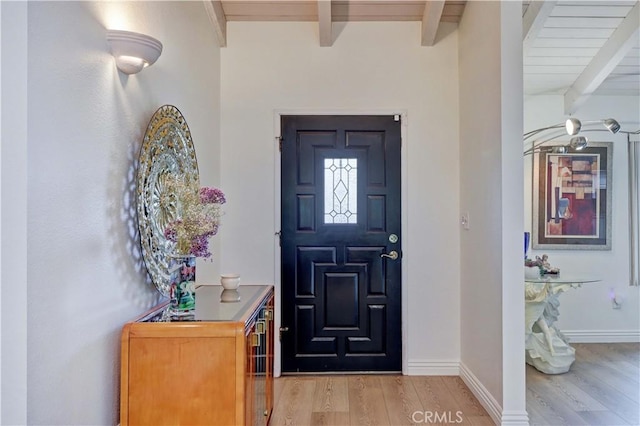 entryway with beamed ceiling and light wood-type flooring