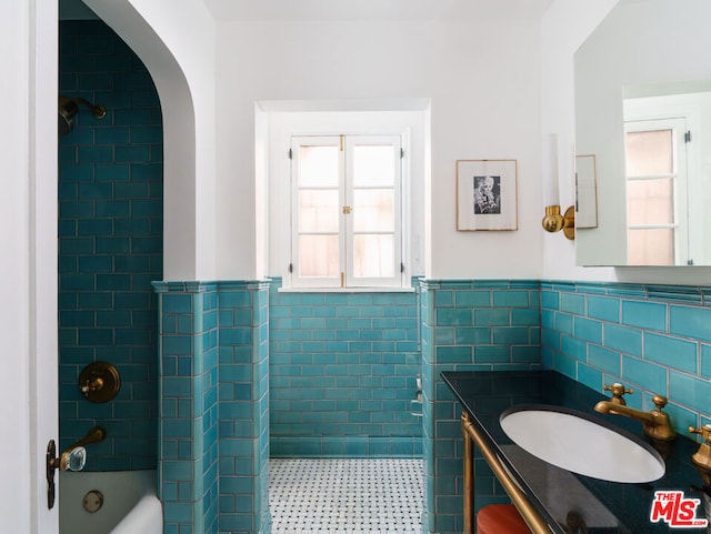 bathroom featuring tile walls, vanity, and tiled shower / bath combo