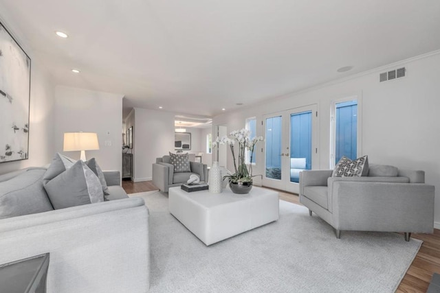 living room featuring french doors, ornamental molding, and light hardwood / wood-style flooring