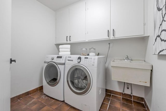 clothes washing area with washer and clothes dryer, cabinets, and dark tile flooring