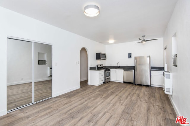 kitchen with ceiling fan, white cabinets, sink, stainless steel appliances, and light wood-type flooring