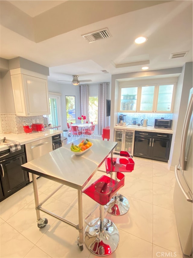 kitchen featuring white fridge, tasteful backsplash, plenty of natural light, and white cabinets