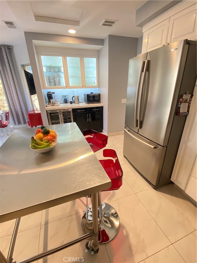 kitchen with appliances with stainless steel finishes, white cabinetry, and beverage cooler