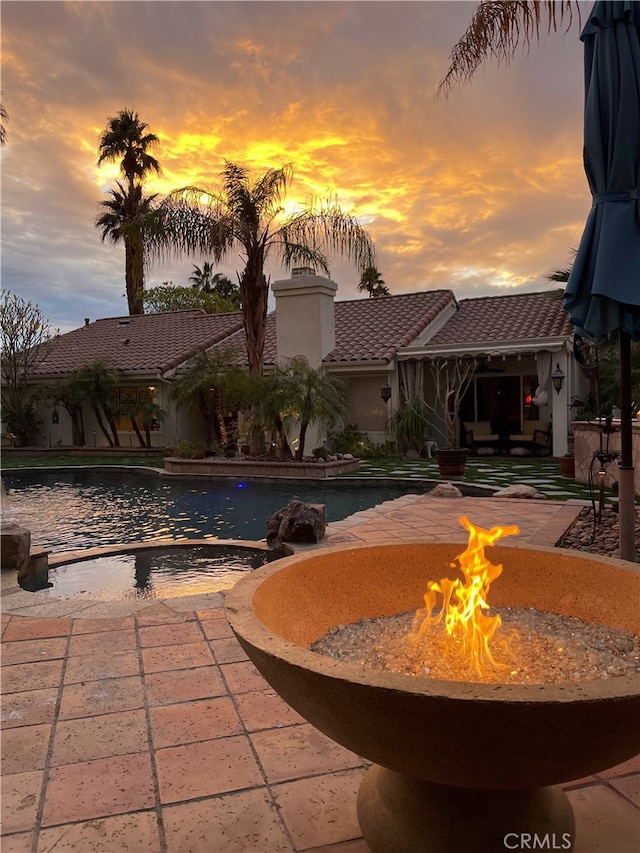 pool at dusk with a patio and an outdoor fire pit