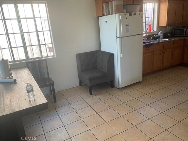 kitchen with black microwave, sink, white fridge, and light tile patterned flooring