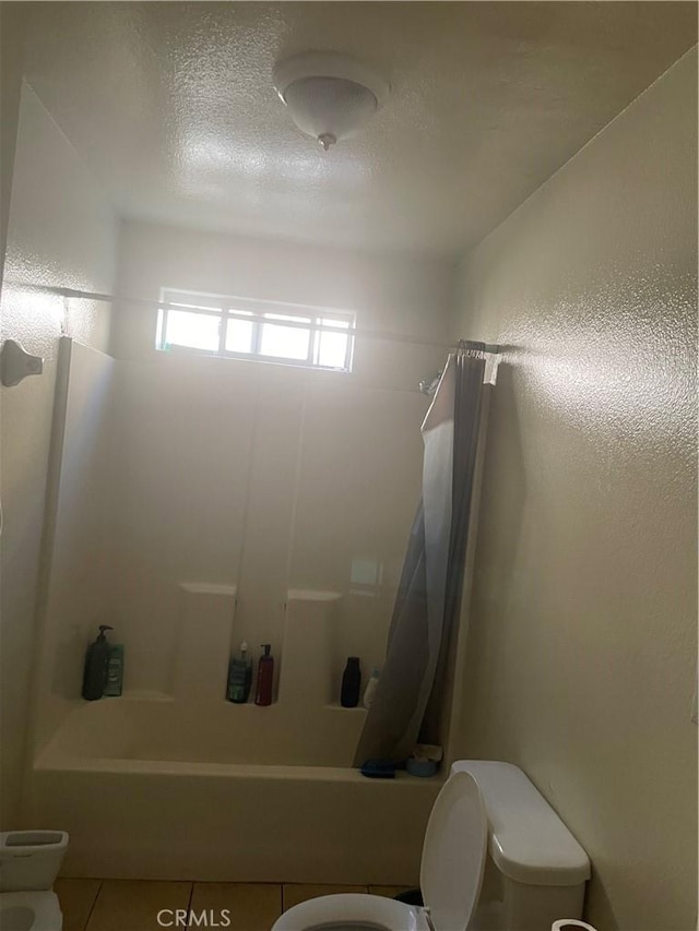 bathroom featuring tile patterned floors, shower / bath combo, and toilet