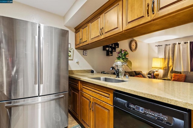 kitchen featuring light stone counters, dishwasher, stainless steel fridge, and sink