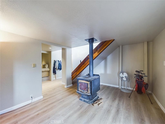 interior space featuring light wood-type flooring, a wood stove, and a textured ceiling