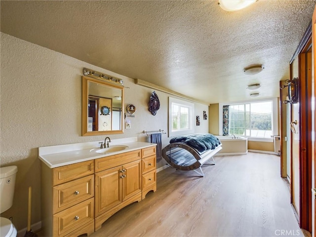 bedroom with a textured ceiling, sink, and light hardwood / wood-style flooring