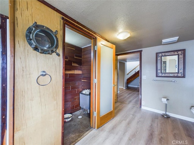 hallway with wood walls, a textured ceiling, and hardwood / wood-style flooring