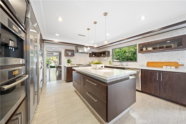 kitchen with pendant lighting, tasteful backsplash, a kitchen island, appliances with stainless steel finishes, and crown molding