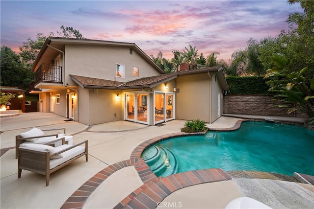 back house at dusk with a balcony and a patio area