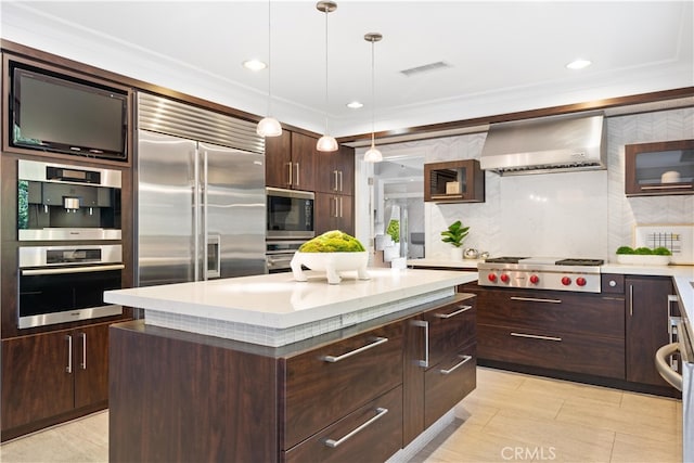 kitchen with a kitchen island, built in appliances, ventilation hood, decorative light fixtures, and ornamental molding