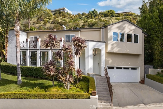 view of front facade featuring a balcony, a front yard, and a garage