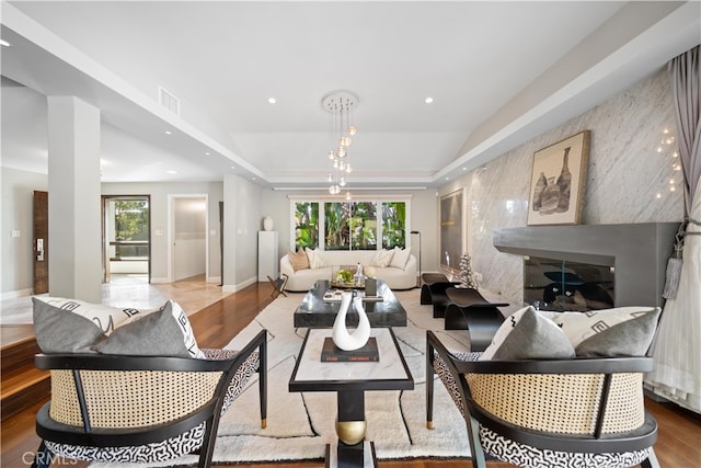 living room with light hardwood / wood-style flooring, a raised ceiling, and a healthy amount of sunlight