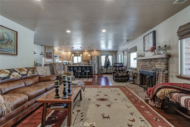 living room with wood-type flooring, a textured ceiling, and a fireplace