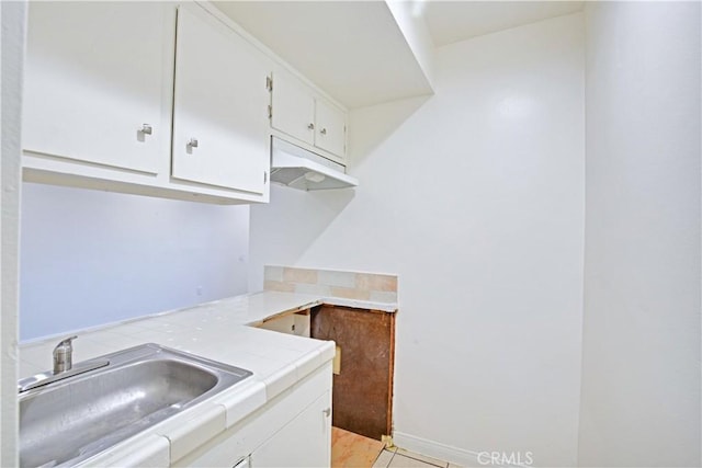 kitchen with sink, tile countertops, white cabinetry, and light tile patterned flooring