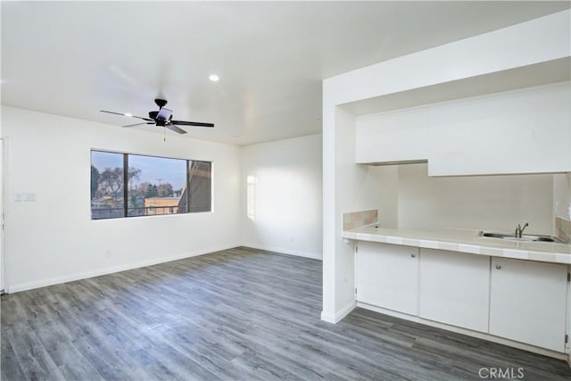 unfurnished living room with ceiling fan, dark hardwood / wood-style floors, and sink