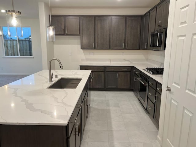 kitchen with sink, decorative light fixtures, light stone countertops, and appliances with stainless steel finishes