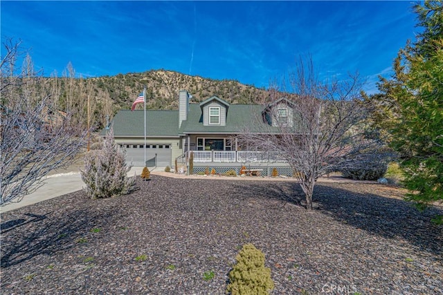 view of front facade with a mountain view, covered porch, and a garage