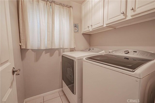 clothes washing area featuring washer and clothes dryer, light tile patterned flooring, and cabinets