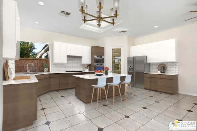 kitchen with a kitchen island, white cabinetry, pendant lighting, and white appliances