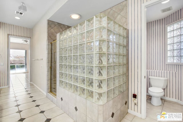 bathroom featuring toilet, an enclosed shower, plenty of natural light, and ceiling fan