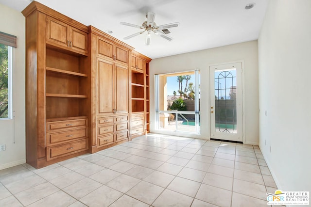 interior space featuring built in desk, light tile patterned floors, a healthy amount of sunlight, and ceiling fan