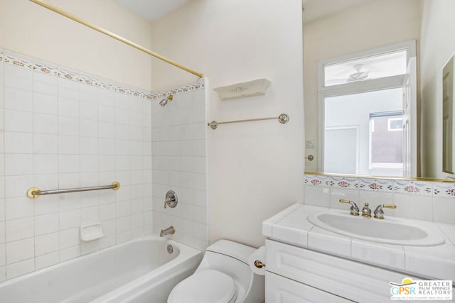 full bathroom featuring vanity, tiled shower / bath combo, and toilet