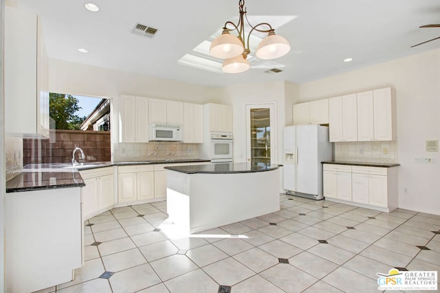 kitchen featuring white appliances, white cabinetry, pendant lighting, and a kitchen island