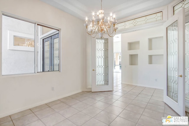 entrance foyer with a notable chandelier, french doors, and light tile patterned floors