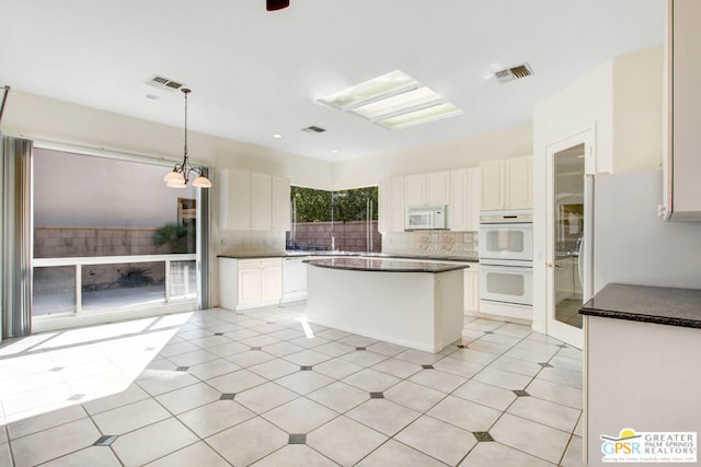 kitchen featuring white appliances, backsplash, a center island, hanging light fixtures, and white cabinets