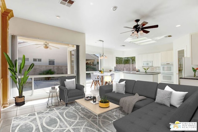 kitchen featuring white appliances, backsplash, white cabinetry, pendant lighting, and light tile patterned floors