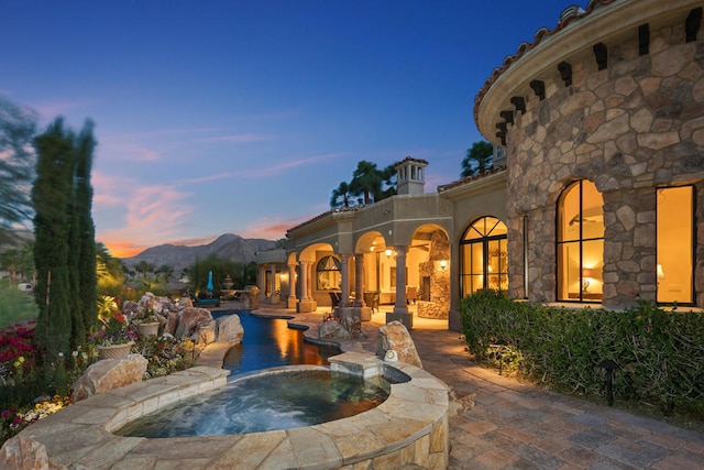 exterior space featuring a patio area, a mountain view, and an in ground hot tub