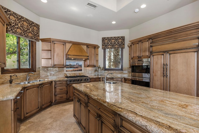 kitchen featuring custom exhaust hood, decorative backsplash, appliances with stainless steel finishes, sink, and light stone counters