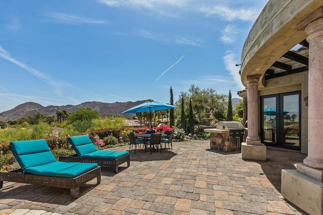 view of patio with french doors, a mountain view, an outdoor kitchen, and a grill