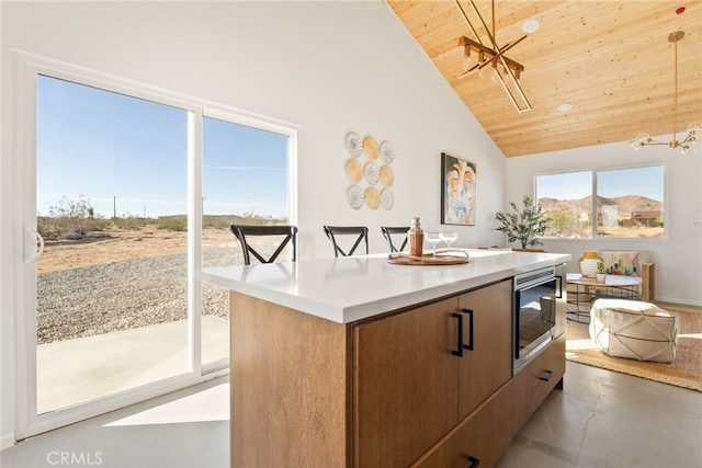 kitchen with a kitchen island, wood ceiling, stainless steel microwave, concrete floors, and pendant lighting