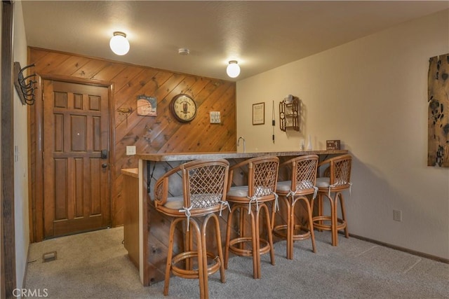 bar featuring light carpet and wood walls